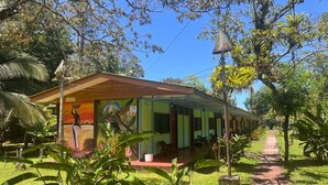 A single-story building with a covered porch, surrounded by lush greenery and a clear sky. - Ilan Ilan tortuguero (Colorado)