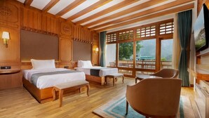 A hotel room with a wooden ceiling, a large bed, a smaller bed, a chair, and a TV. - Amba Paro (Paro)
