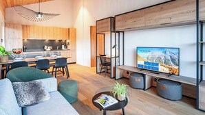 Ein modernes Wohnzimmer mit einer Couch, einem Couchtisch und einem Fernseher, der eine Berglandschaft zeigt.