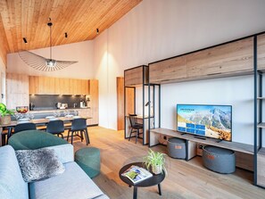 A modern living room with a sofa, a coffee table, and a TV displaying a mountain landscape. - Lovely apartment for 6 people with WIFI, TV, terrace and pets allowed (Les Collons)
