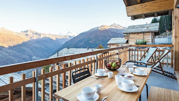Ein Holzespeisetisch mit weißem Geschirr und Besteck, mit Blick auf eine Berglandschaft.