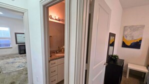 Een kamer met een badkamer, een bureau en een schilderij aan de muur.