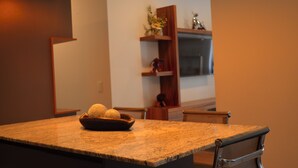 Una cocina con encimera de granito, una silla y una estantería con adornos.
