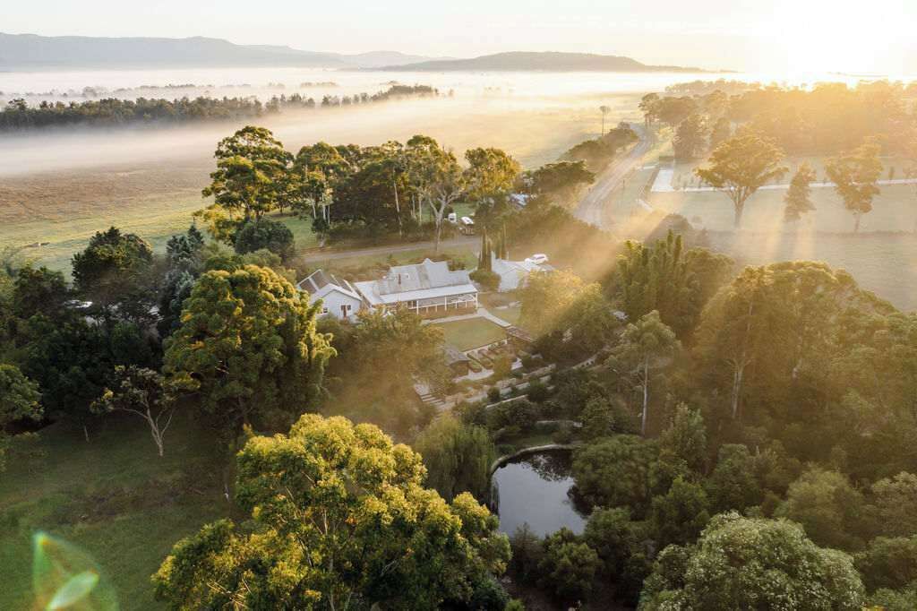 Uma propriedade extensa com vistas amplas, um lago e diversas árvores.