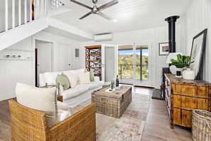 A spacious living room with a white sofa, wicker furniture, a ceiling fan, and a view through large glass doors. - 'Meadow Mist' Private Garden Estate with Outdoor Spa Near Berry (Far Meadow)