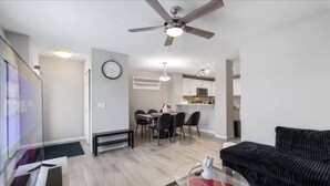 Un salon moderne avec un canapé, une table basse en verre et un coin repas avec des chaises.