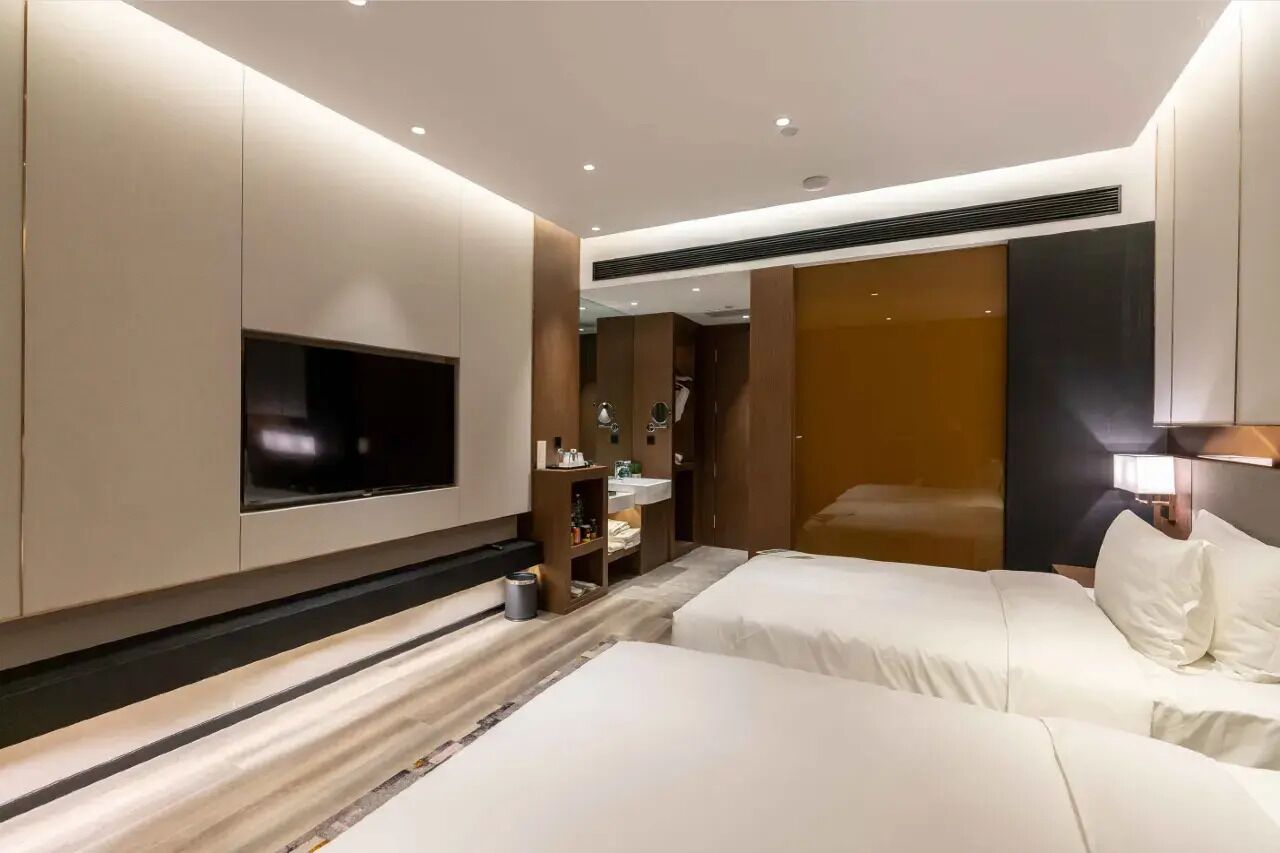 Habitación de hotel con dos camas, televisión, armario y baño.