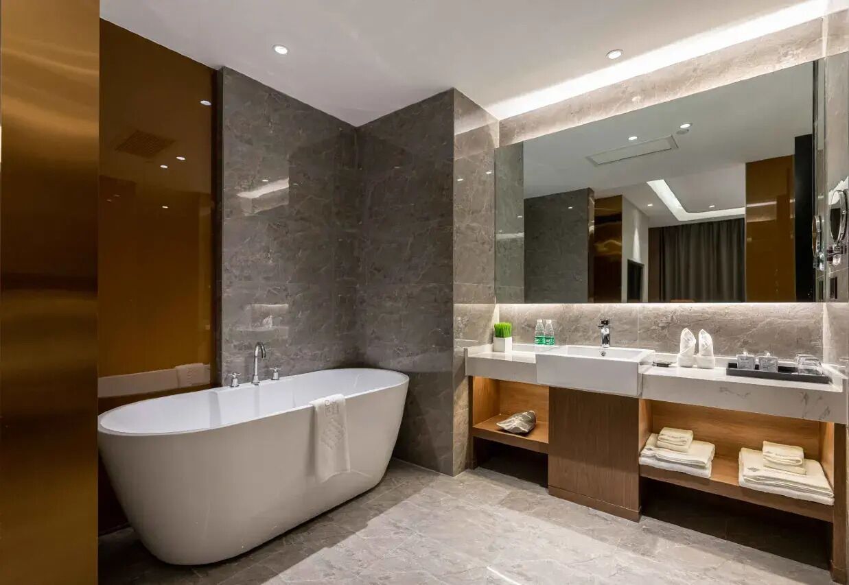 A modern bathroom with a freestanding bathtub, a vanity with a mirror, and a shelf with towels.
