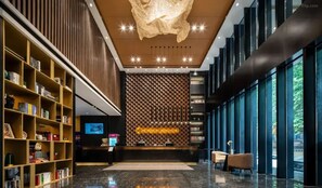 A modern lobby with a reception desk, bookshelves, a large chandelier, and a patterned wall. - Giorgio Morandi Hotel - Jinan Jiefang  (Jinan)
