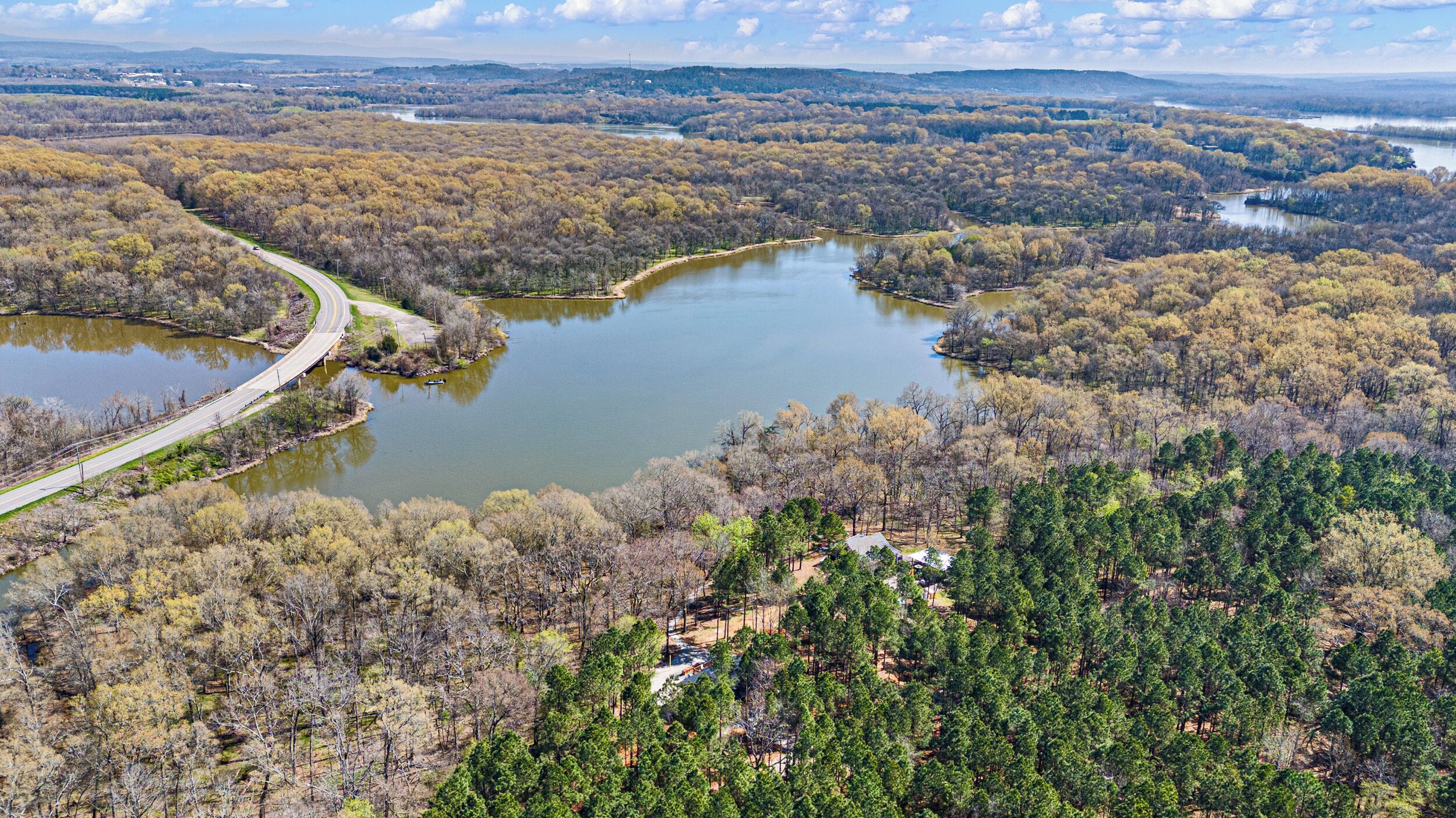 A river winding through a forested area with a road curving alongside it.
