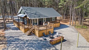 Une cabane dotée d’une terrasse, de meubles de jardin et d’un foyer extérieur.