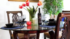 A dining table with a glass top, surrounded by chairs, a vase with flowers, and a bottle of wine. - Newly renovated 3 bedroom house near Allen premium outlets (Allen)