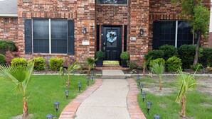 A brick building with a black door, a wreath, and a pathway leading to the entrance. - Newly renovated 3 bedroom house near Allen premium outlets (Allen)