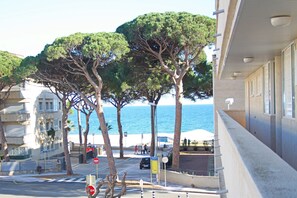 A coastal building with a view of the sea, trees, and a street with a stop sign. - Sol Daurat Apartment by the Sea (Cambrils)