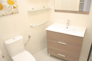 A bathroom with a toilet, a sink, a mirror, and a towel rack. - Sol Daurat seafront apartment (Cambrils)