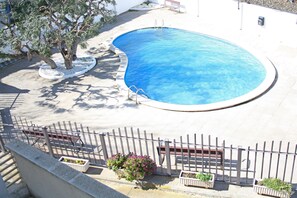 A swimming pool with a surrounding fence, benches, and potted plants. - Sol Daurat seafront apartment (Cambrils)