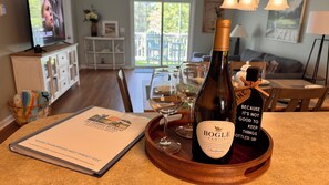 A bottle of Bogle Family wine on a wooden tray with two wine glasses, a menu, and a television in the background. - Fairway Retreat at Barefoot Resort • Pond View • Minutes to Beach (North Myrtle Beach)