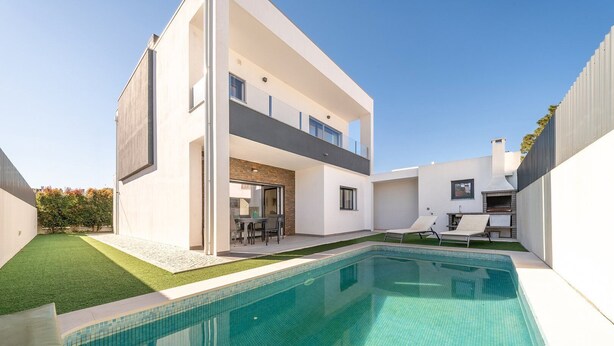 Ein modernes, zweistöckiges Haus mit Swimmingpool, Außenbereich mit Sitzgelegenheiten und Grillplatz.