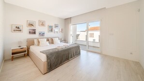 Ein Schlafzimmer mit Bett, Nachttisch und Blick durch eine Schiebetür.