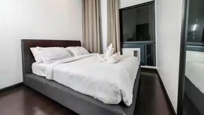 Moderni hotellihuone, jossa on suuri sänky, taulutelevisio ja näkymä kaupunkiin.