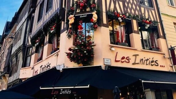 Un bâtiment sur lequel on peut lire l’inscription « Les Inities… » et qui est décoré d’une couronne de Noël.