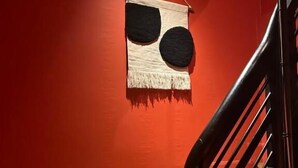 Un escalier avec un mur rouge et une rampe noire.