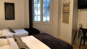 Une chambre avec deux lits, une fenêtre, un téléviseur et une chaise.