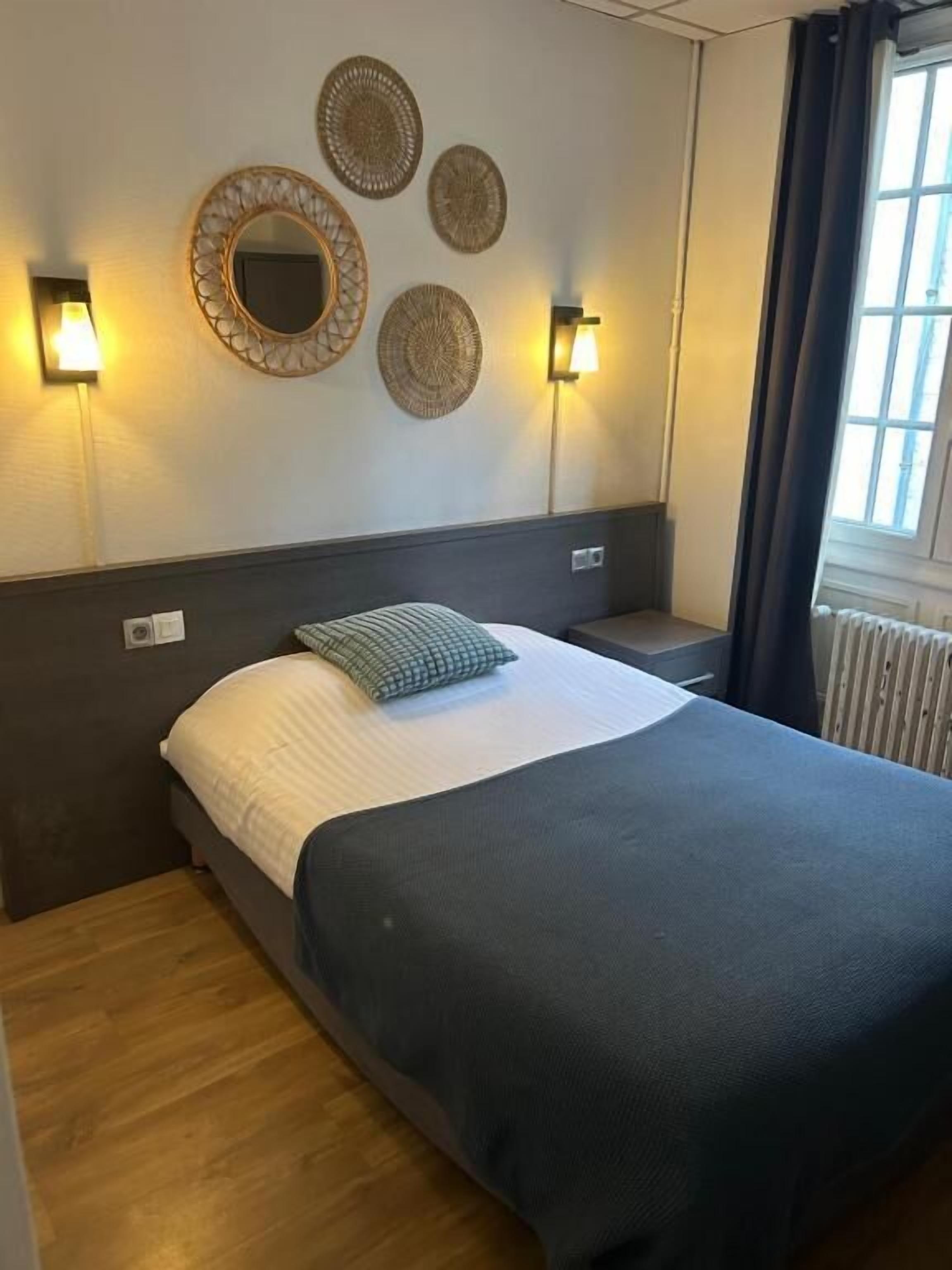 Una habitación de hotel con una cama, dos lámparas de pared y decoración en la pared.