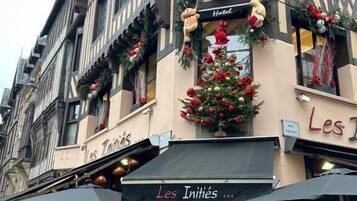 A building with a sign reading 'Les Inities' and a Christmas tree decorated with ornaments.