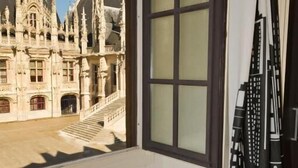 Une salle de bain avec une baignoire, une fenêtre donnant sur un bâtiment historique et un rideau.