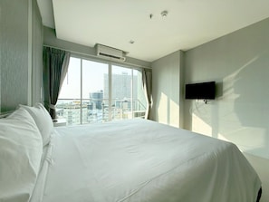 Hotelkamer met een groot bed, een flatscreen televisie aan de muur en een raam met uitzicht op de stad.