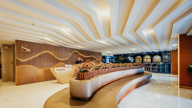 A modern reception area with a curved seating arrangement, a reception desk, and a decorative wall with vertical lines. - Sea Dream Jomtien Beach (Pattaya)