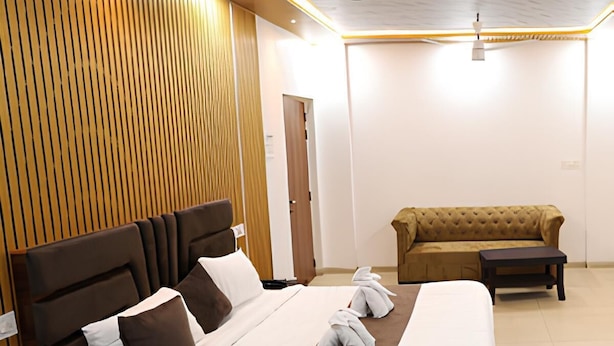 Une chambre d’hôtel avec un grand lit, un canapé, une petite table et un ventilateur de plafond.