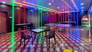 Une pièce avec un sol à carreaux, des tables de baby-foot et des tables de billard.