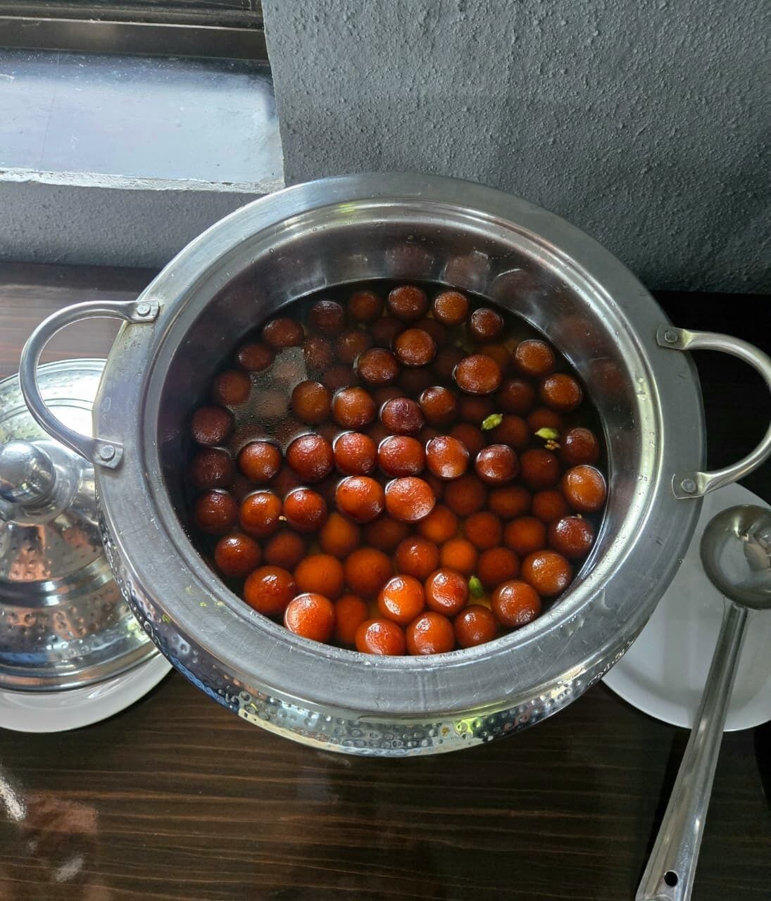 Une casserole en acier inoxydable contenant des objets ronds de couleur orange, qui pourraient être des aliments, posée sur une surface en bois.
