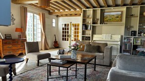 Ein Wohnzimmer mit Klavier, Bücherregal, Couchtisch und Sofa.