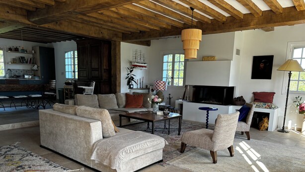 Ein geräumiges Wohnzimmer mit großem Sofa, Sesseln, Couchtisch und Kamin.