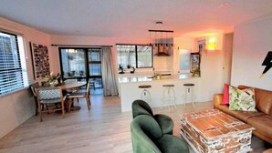 A living room with a sofa, a coffee table, and a dining area with chairs and a table. - Coastal Retreat - 3 min walk to the beach 
Open for Monthly stays (Whangaparāoa)