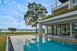 Ein modernes Haus mit Swimmingpool, großen Fenstern und Blick auf die Landschaft.