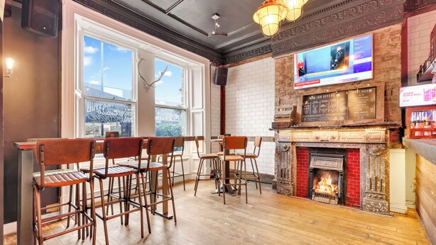Una zona de bar con chimenea, taburetes, una pantalla de televisión y una pared de ladrillo.