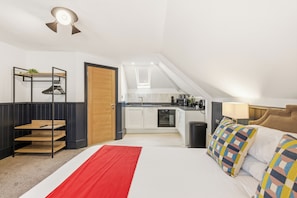A bedroom with a bed, a red throw, a nightstand, and a bedside table.