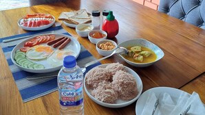 Una mesa de comedor con una variedad de platos, una botella de agua y vistas a la vegetación a través de una ventana.