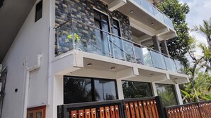Un immeuble de deux étages doté d’un balcon, d’une façade en pierre et d’une entrée fermée par un portail.