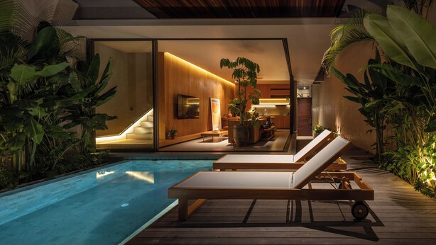 A modern pool area with lounge chairs, a wooden deck, and indoor plants. - Savara Villas Canggu (Canggu)