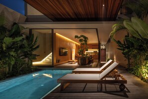 Un área de piscina moderna con sillas de descanso, una terraza de madera y plantas de interior.