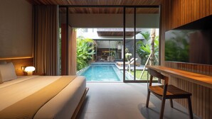 A modern hotel room with a large bed, a desk, a TV, and a view of a swimming pool and outdoor area. - Savara Villas Canggu (Canggu)