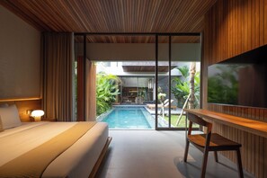 Habitación de hotel moderna con una cama grande, un escritorio, un televisor y vistas a una piscina y zona exterior.