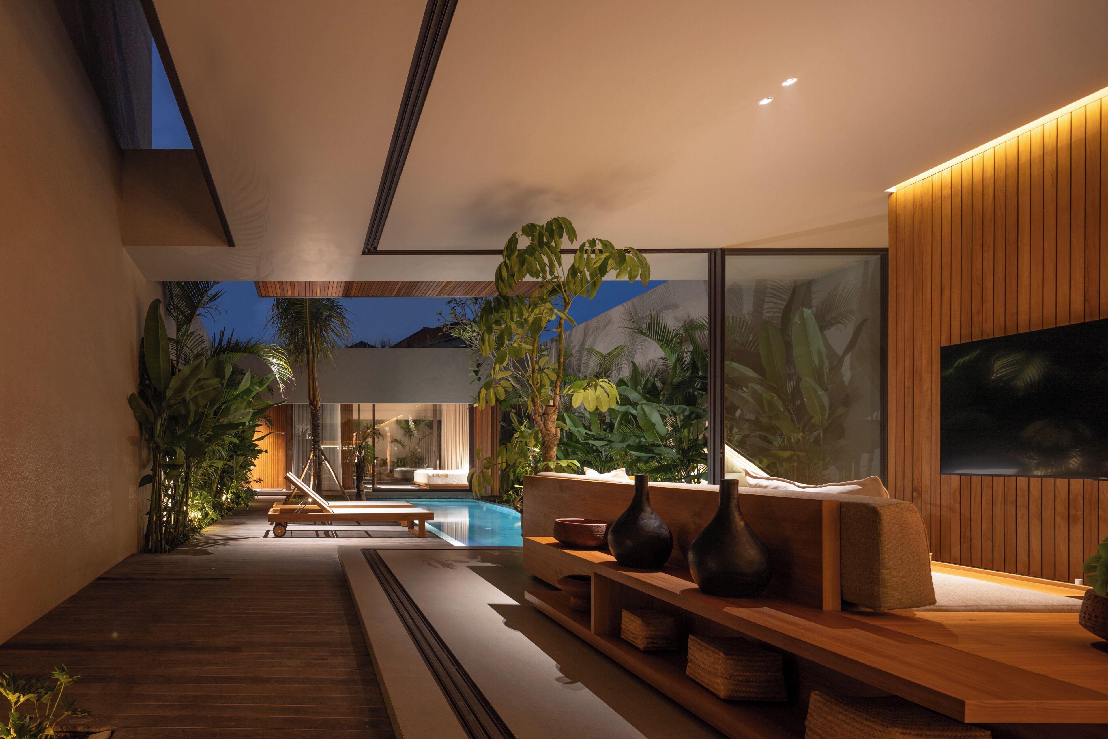 A modern interior with a pool, wooden furniture, and large windows.
