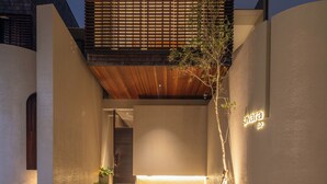 A modern building with a flat roof, a wooden slatted section, and a small tree in the foreground. - Savara Villas Canggu (Canggu)