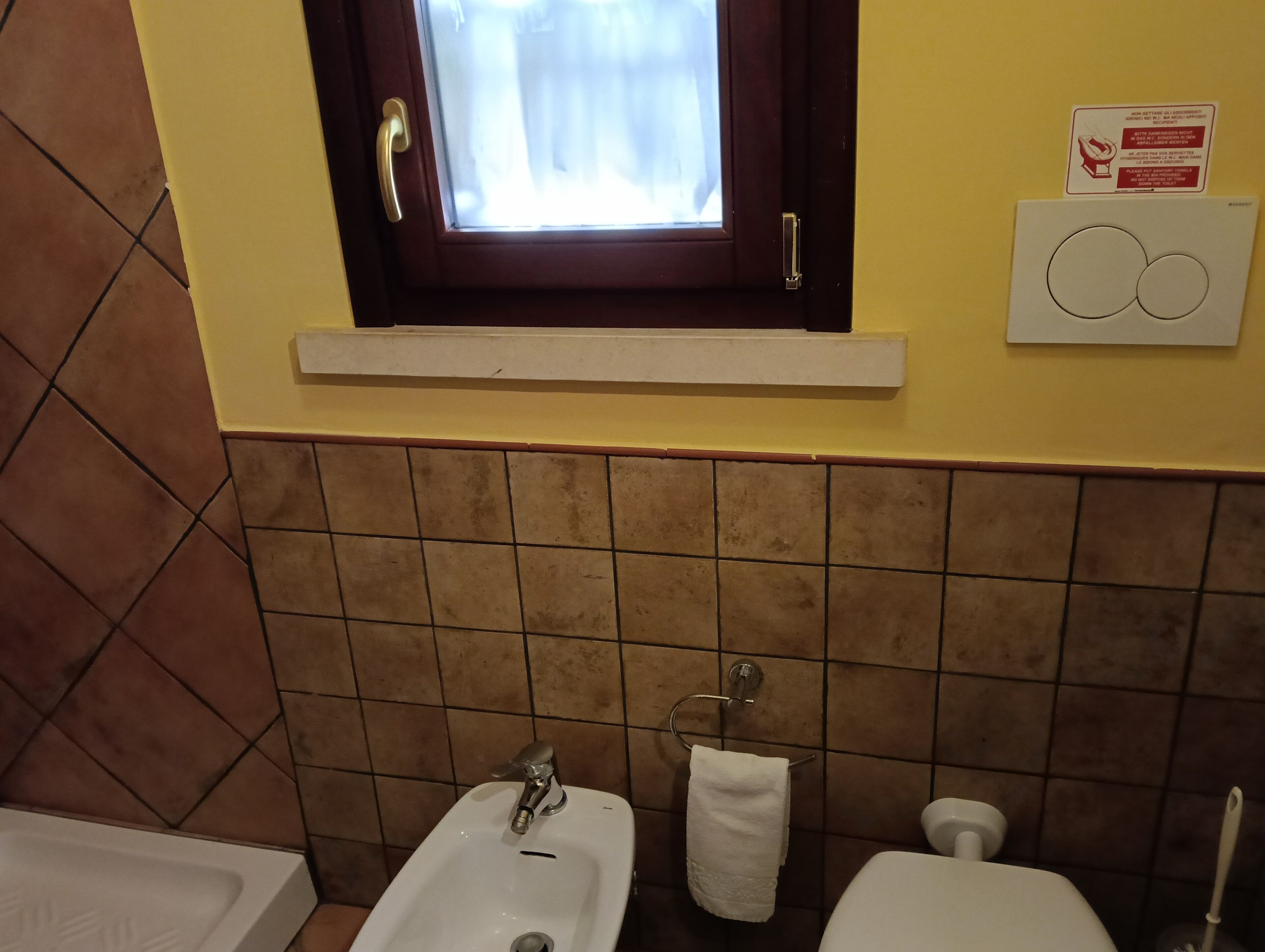 Ein Badezimmer mit Fenster, Waschbecken, Toilette und Handtuchhalter.